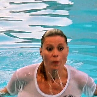 Leslie Easterbrook in a see-through shirt swimming in a pool'